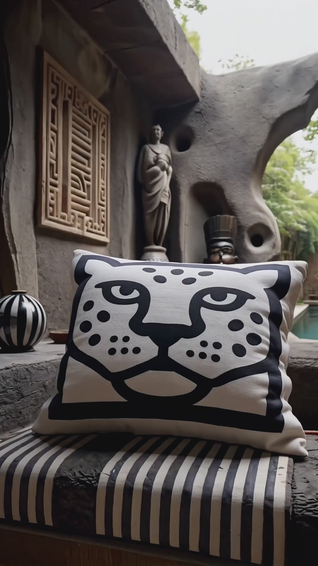 Décoration intérieur : un banc en pierre avec un coussin remarquable au milieu, orné d'un motif graphique audacieux représentant un visage tribal, mettant en valeur les détails complexes de son design